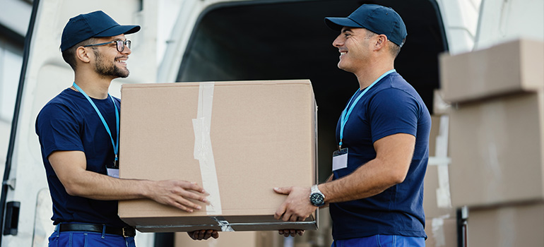 two movers in front of the house carrying tables