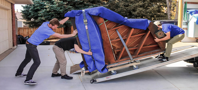 3 movers TXrrying wrapped piano up the stairs