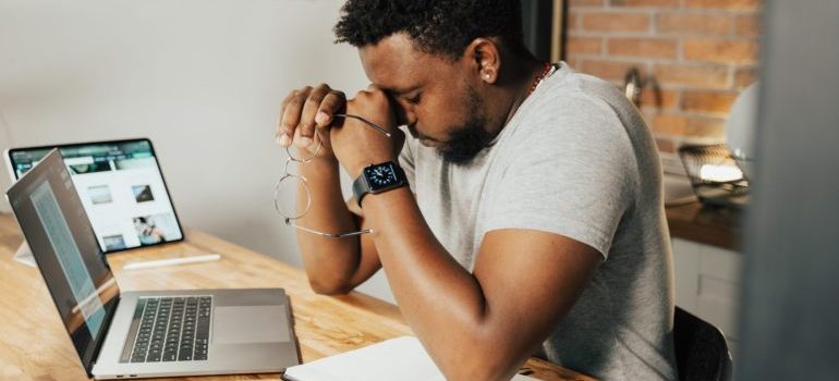 man sitting with his laptop, holding his head and thinking about Moving Your Home Office